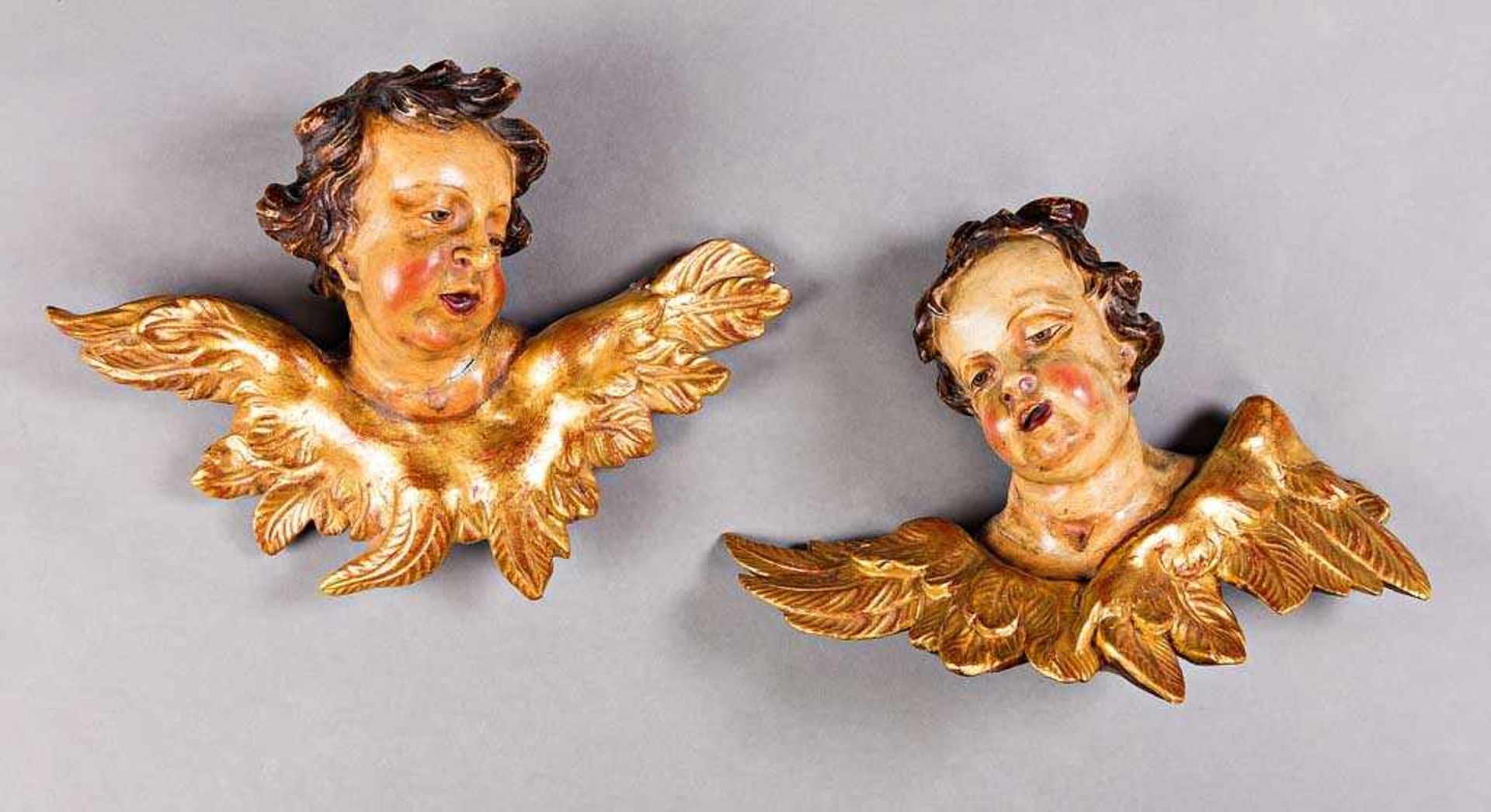 Paar geflügelte Engelsköpfe. Polychrom und golden gefasst. Wohl 19. Jh. H 26 cm, L 36 cm