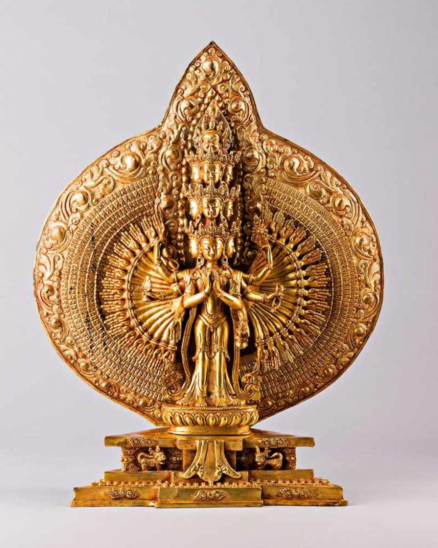 Stehender Bodhisattva Avalokitesvara auf getrepptem Sockel. Ornamental getriebene Aureole. Bronze