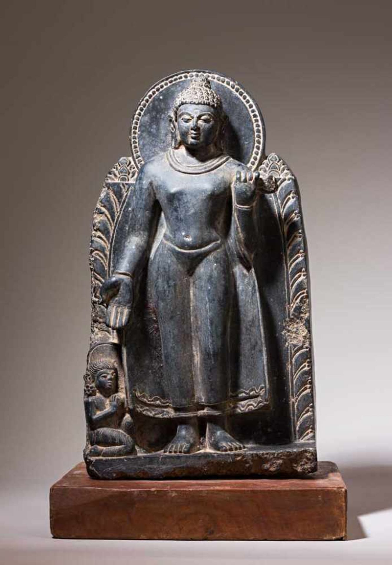 Kleine Buddha-Stele. Auf Plinthensockel stehender Buddha in Tribhanga Asana. Zu seinen Füßen kniende