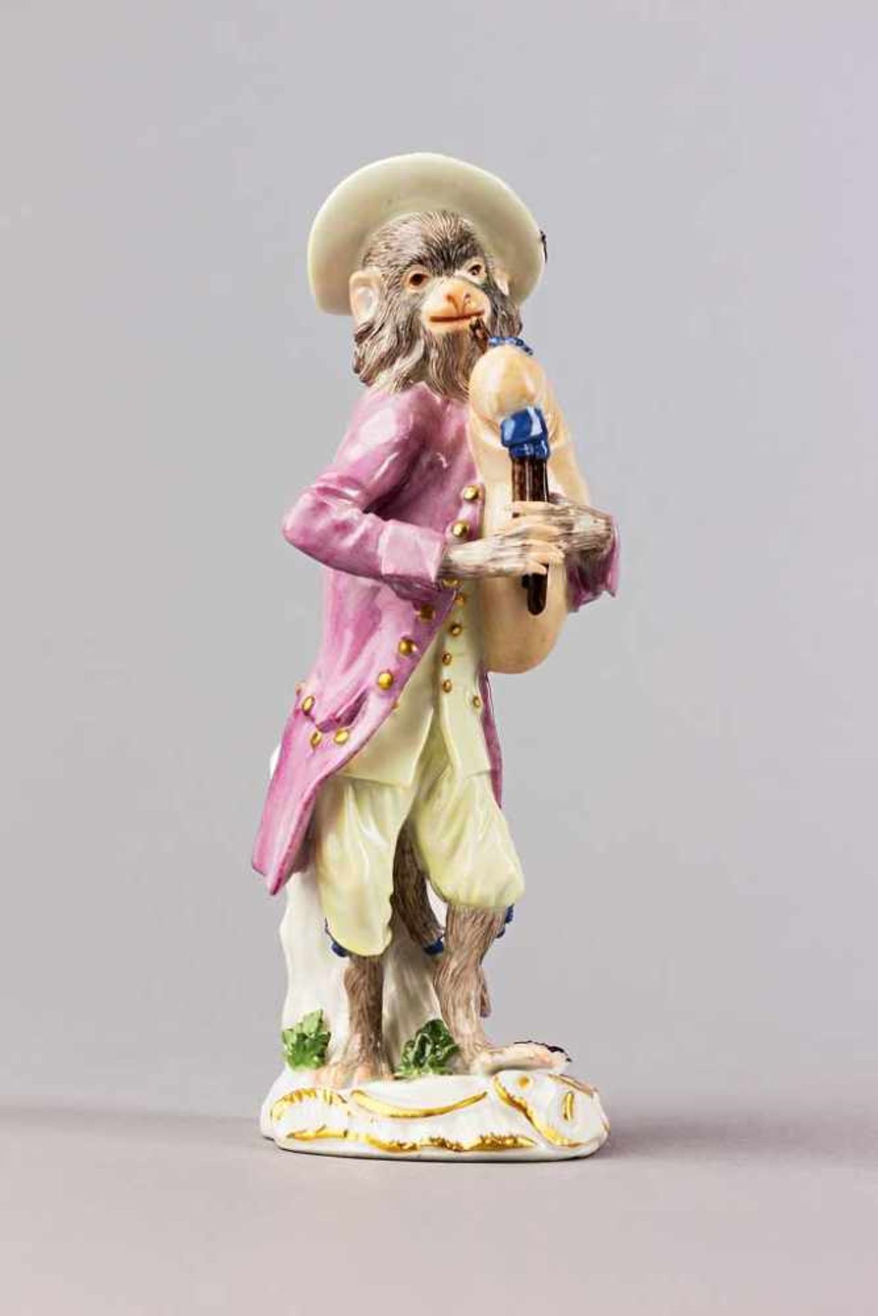 Dudelsackspieler aus der Affenkapelle. Polychrom staffierte Figurine auf mit Blüten belegtem