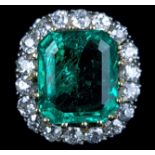 A striking Columbian emerald and diamond cluster ring, c1965, the rectangular shaped cut cornered
