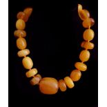 A vintage amber type bead necklace composed of twenty five graduated ovoid and wheel shaped beads,