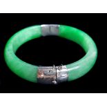 A Chinese jadeite bangle, the two apple green coloured jade sections with white metal coloured hinge