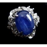 A cabochon sapphire and diamond ring set in white metal, the central domed stone within florets