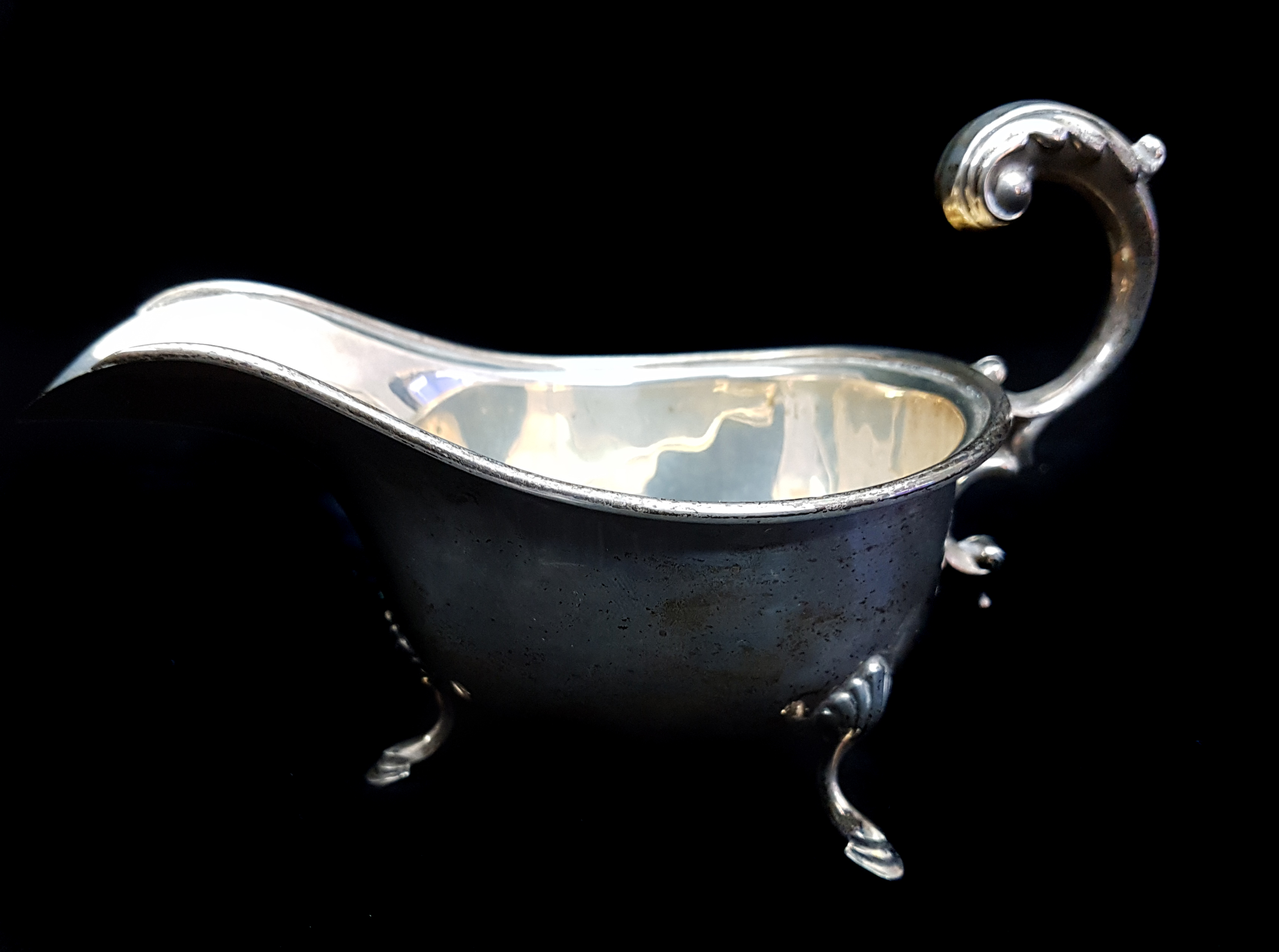 A silver sauceboat, on three volute feet with 'c' scroll handle, Birmingham 1935, kings & queens