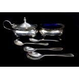 A silver mustard pot and salt cellar, each on four volute feet, oval with shaped piecrust rims,