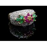 A diamond, emerald and ruby ring, formed as a ruby flower with yellow diamond centre, flanked by