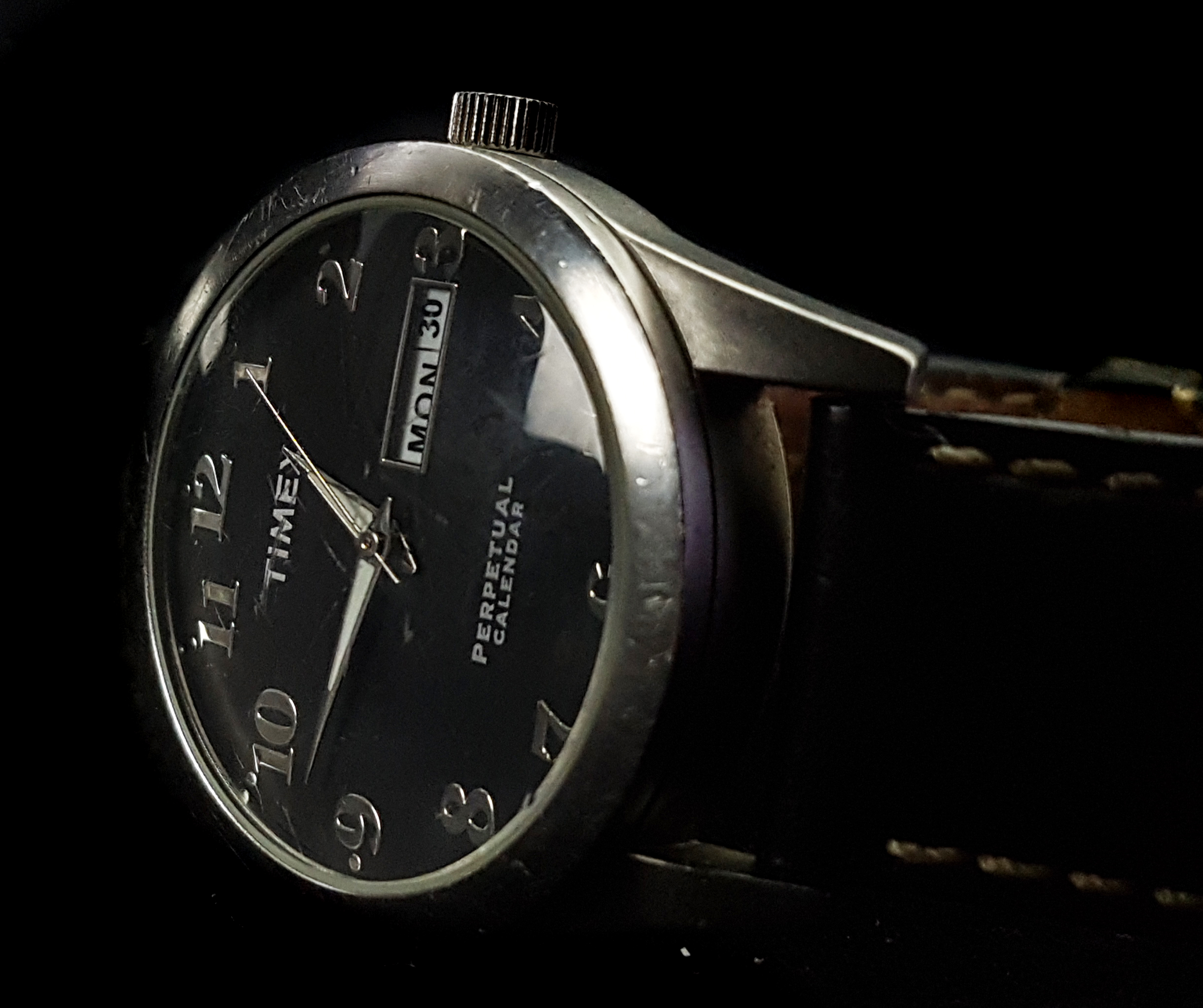 A Timex perpetual calendar wristwatch. Stainless steel, black dial with rectangular day and date