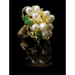 A pearl, emerald and diamond cluster ring formed as a flower with oval pearl petals, diamond stamens