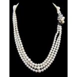 A three strand graduated cultured pearl necklace with diamond and pearl clasp of three pearls set in