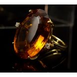 An Orange Topaz dress ring, the large oval stone 2.5cm max flanked by two round brilliant cut