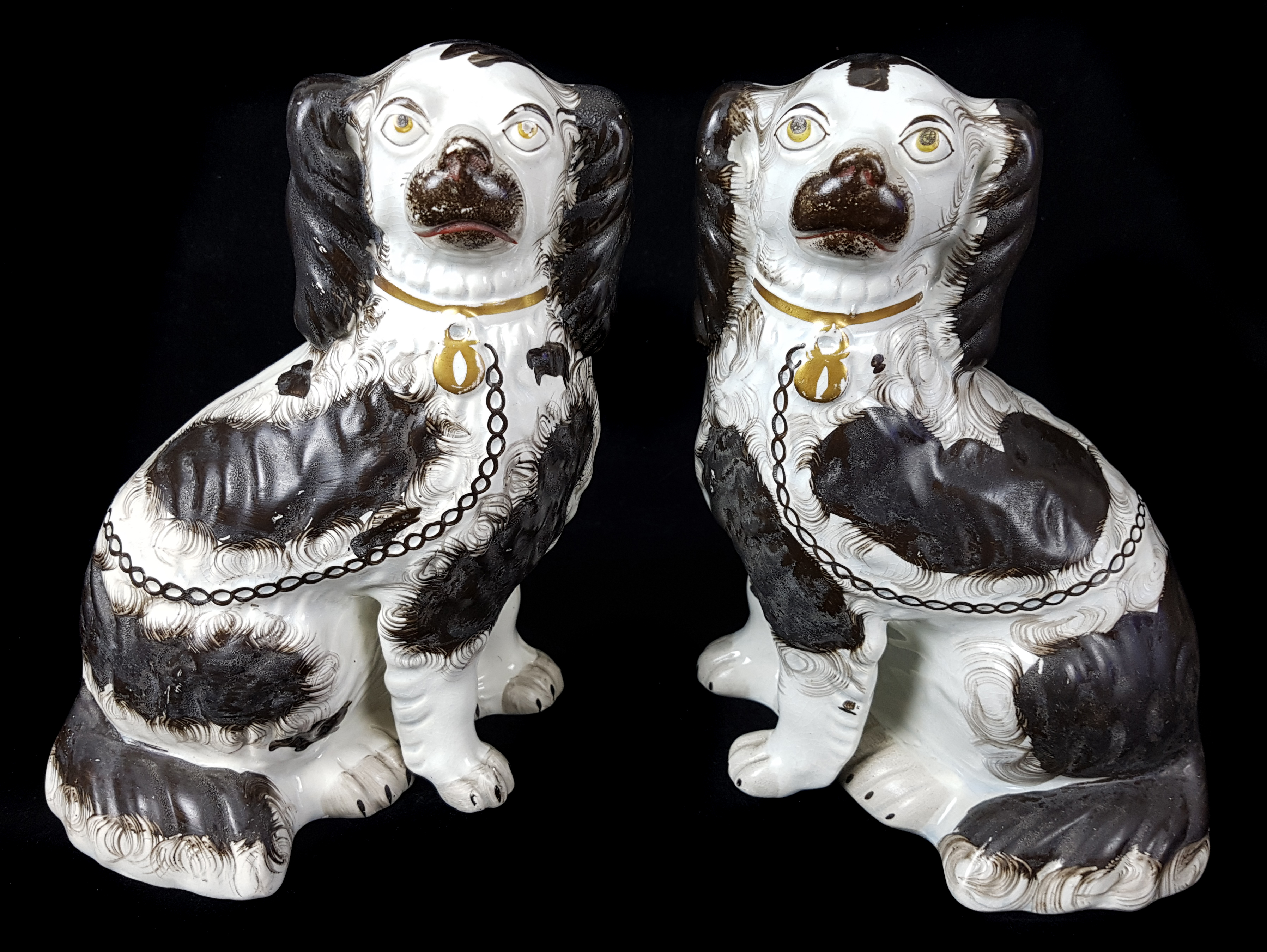 A pair of Staffordshire pottery spaniels, c1860, modelled seated with separate front leg, gilt