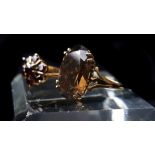 A 9ct gold dress ring set with oval smokey topaz; and a 9ct garnet set flower form ring (2)