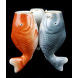 A Japanese porcelain vase formed as three fish resting on their tails, coloured in black, red and