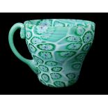 A Tosso brothers millifiori glass teacup and saucer, green and blue canes with red centres on a whit