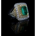 An Emerald and Diamond three tier square cluster ring, with diamond set shoulders, central Columbian