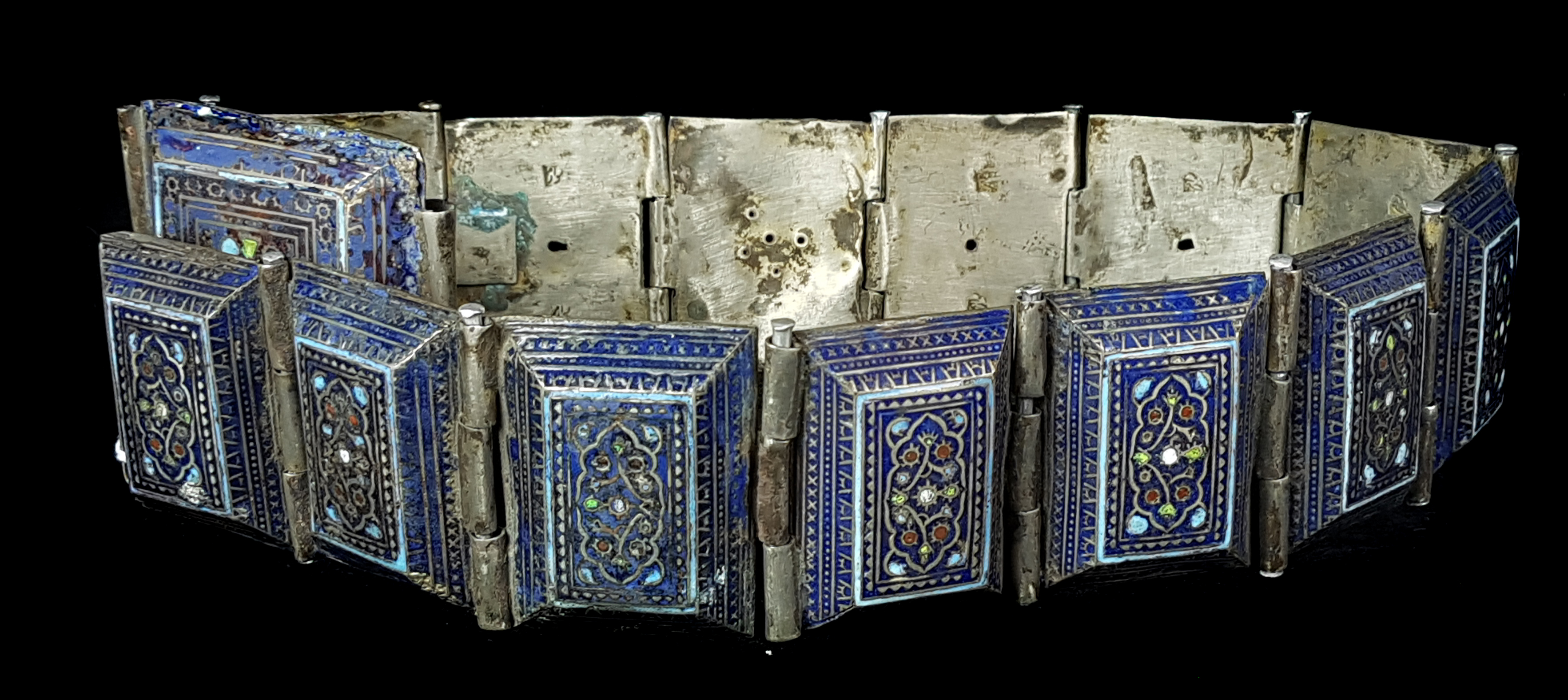 A Middle Eastern enamelled in white metal belt, each link of hollow bevelled rectangular form,