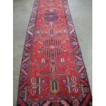 PERSIAN HERIZ RUNNER, overall decorated with geometric designs on a red ground. 330 x 90cm.