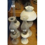 Four glass oil lamps with glass chimneys, one with white glass shade.