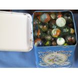 Tin of assorted coloured marbles.