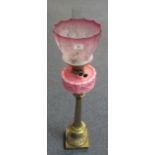 Early 20th Century double burner oil lamp with pink relief moulded glass reservoir on a heavy brass