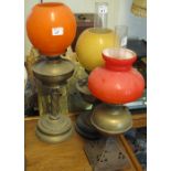 Three brass oil lamps with coloured glass shades, two with chimneys.
