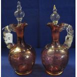 Pair of cranberry glass ewers with clear shell moulded loop handles,