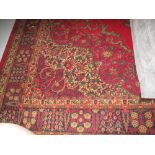 Large Persian style geometric and foliate rug on a red ground.