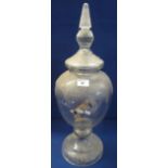 Large clear glass pedestal urn with cover, having faceted, pointed finial, together with wooden tap.