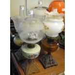 Four double burner oil lamps with glass reservoirs and cast metal bases,