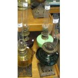 Four brass burner oil lamps with glass reservoirs, three with pierced cast metal bases,