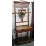 Edwardian oak hall stand with shield shaped mirror back and floral, tiled decoration.