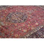 PERSIAN HARYS RED GROUND CARPET with blue medallion to the red floral field, within a multi-banded