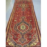 PERSIAN GEOMETRICALLY DECORATED RED GROUND RUNNER with tarantula and lozenge panels within a