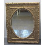 LARGE LATE 19TH CENTURY GILT FRAMED MIRROR, overall with relief foliate decoration around an oval