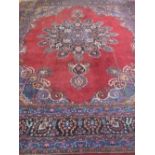 LARGE EASTERN PERSIAN MESHED CARPET overall decorated with a foliate medallion on red ground with