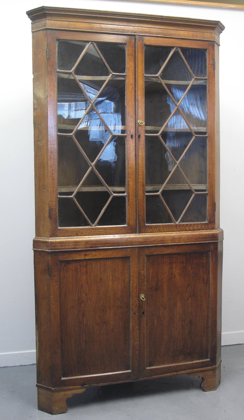EARLY 19TH CENTURY WELSH OAK DOUBLE CORNER CABINET, having moulded and geometrically inlaid frieze