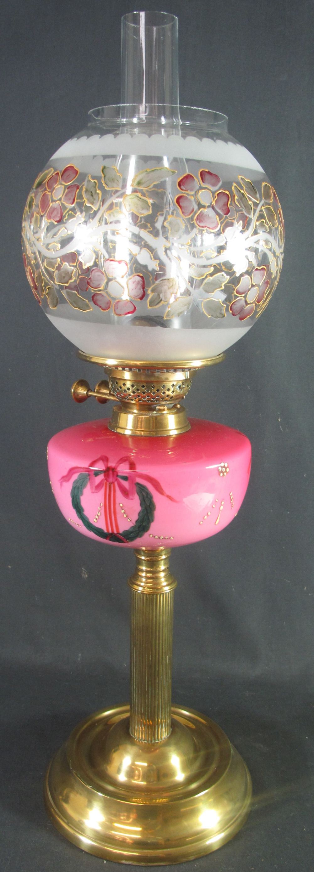 EARLY 20TH CENTURY BRASS DOUBLE BURNER OIL LAMP with pink ceramic reservoir, having painted enamel
