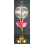 EARLY 20TH CENTURY BRASS DOUBLE BURNER OIL LAMP with pink ceramic reservoir, having painted enamel