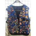 Blue padded zip up waistcoat with multiple Elvis Presley memorabilia attached including badges,