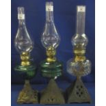 Group of three early century brass oil lamps with glass reservoirs and pierced cast metal bases,