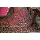 Persian Harys red ground carpet with blue medallion to the red floral field,