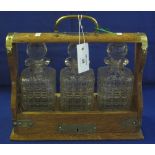 Early 20th Century oak brass mounted Tantalus containing three square section decanters and