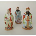 Three Chinese handpainted porcelain figures of holy men on wooden bases. Early 20th century.