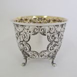 A sterling silver cup decorated with engraved and repousse flowers on four feet, by Sibray, Hall &