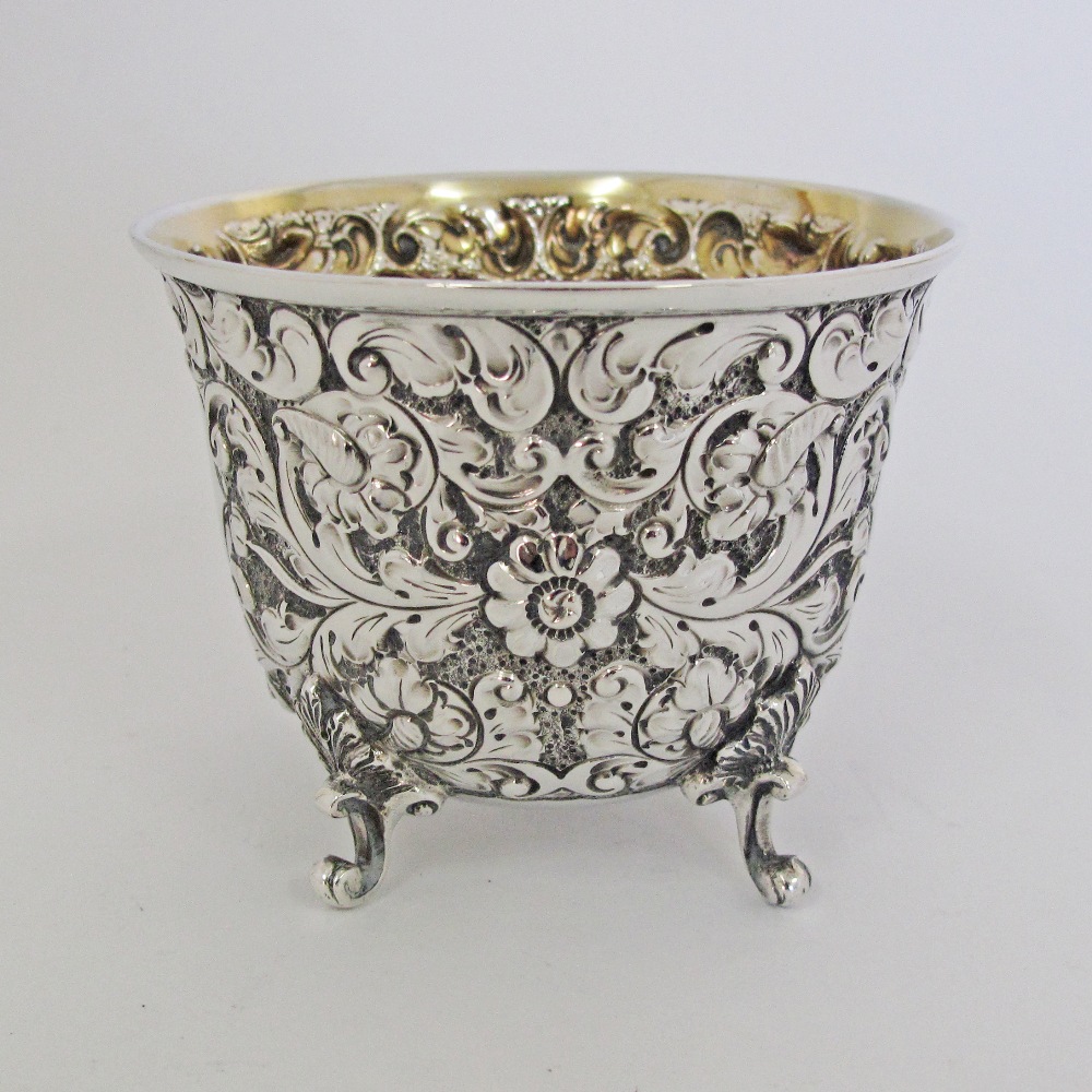 A sterling silver cup decorated with engraved and repousse flowers on four feet, by Sibray, Hall & - Image 2 of 5