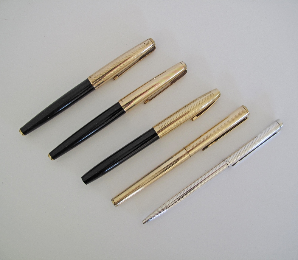 A collection of five pens comprising three fountain pens with gold cups, a gold ball pen and a