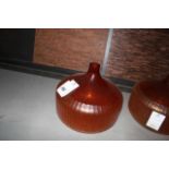Glass Vase Orange boasts a wide, round base and short bottleneck. Wraparound ribbed patterning