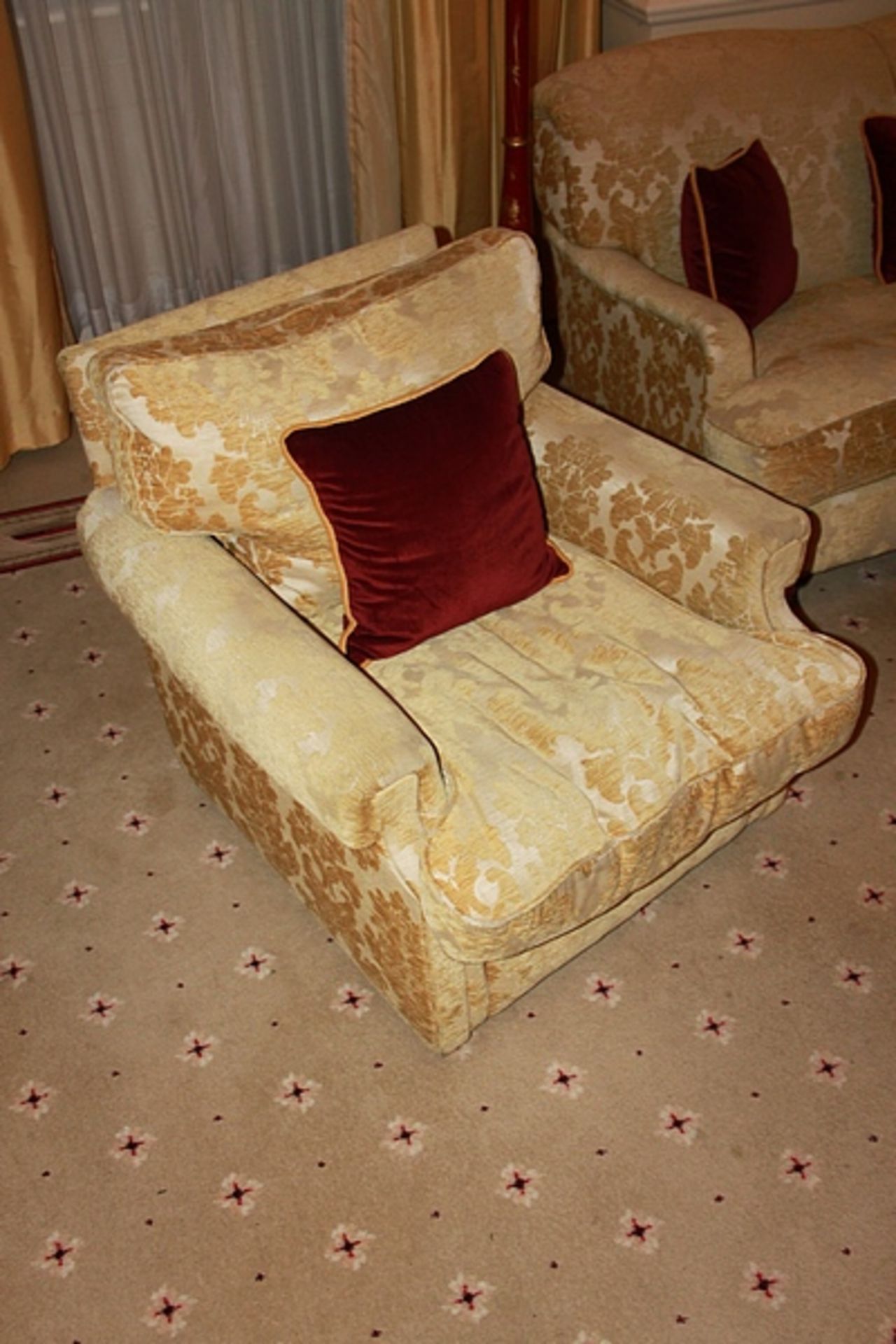 A traditional easy armchair upholstered in a gold broccade fabric mounted on solid legs 800mm x