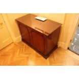 A mahogany two door cabinet the moulded top above a pair of half drawers and brushed slide tray with
